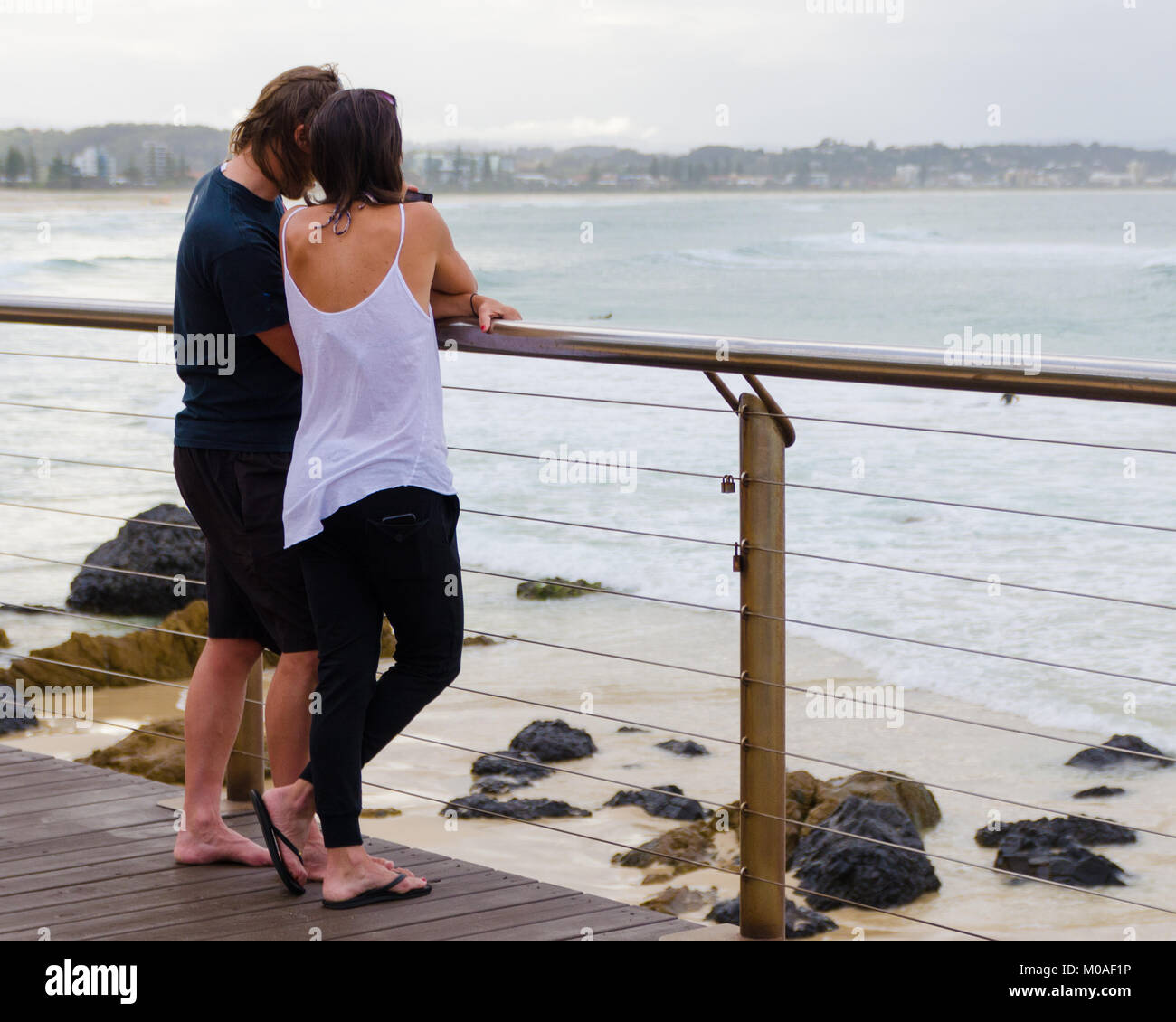 Paar ruhigen Moment genießen Sie gemeinsam am Strand. Touristische lean von Boardwalk Geländer mit Blick auf malerische Seenlandschaft. Stockfoto