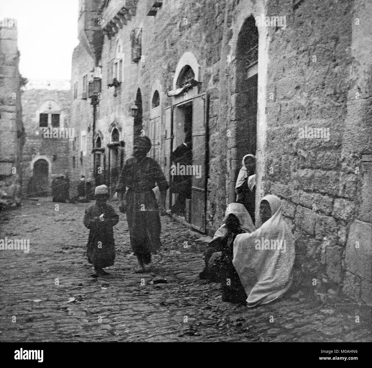 Einen späten 19. oder frühen 20. Jahrhundert schwarz-weiß Foto zeigt eine Straßenszene in Bethlehem in Palästina, oder modernen Israel. Ein Mann gesehen werden kann zu Fuß durch die Straße mit seinem Sohn, während Frauen sitzen auf der Seite der Strasse oder in Hauseingängen. Stockfoto
