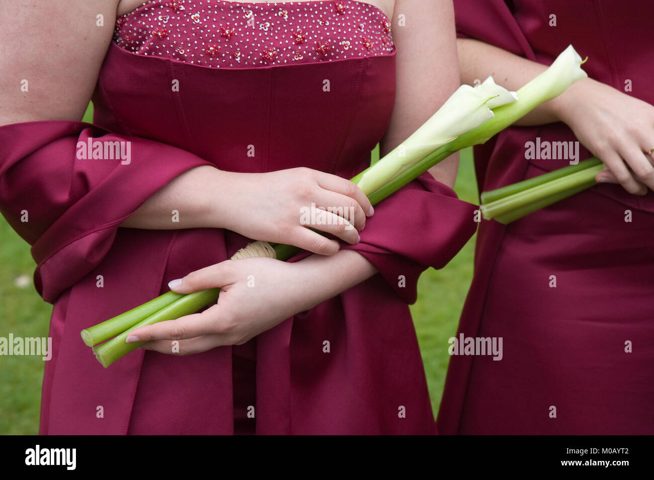 Brautjungfern in roten Kleidern Blumen außerhalb Holding bei einer Hochzeit Stockfoto