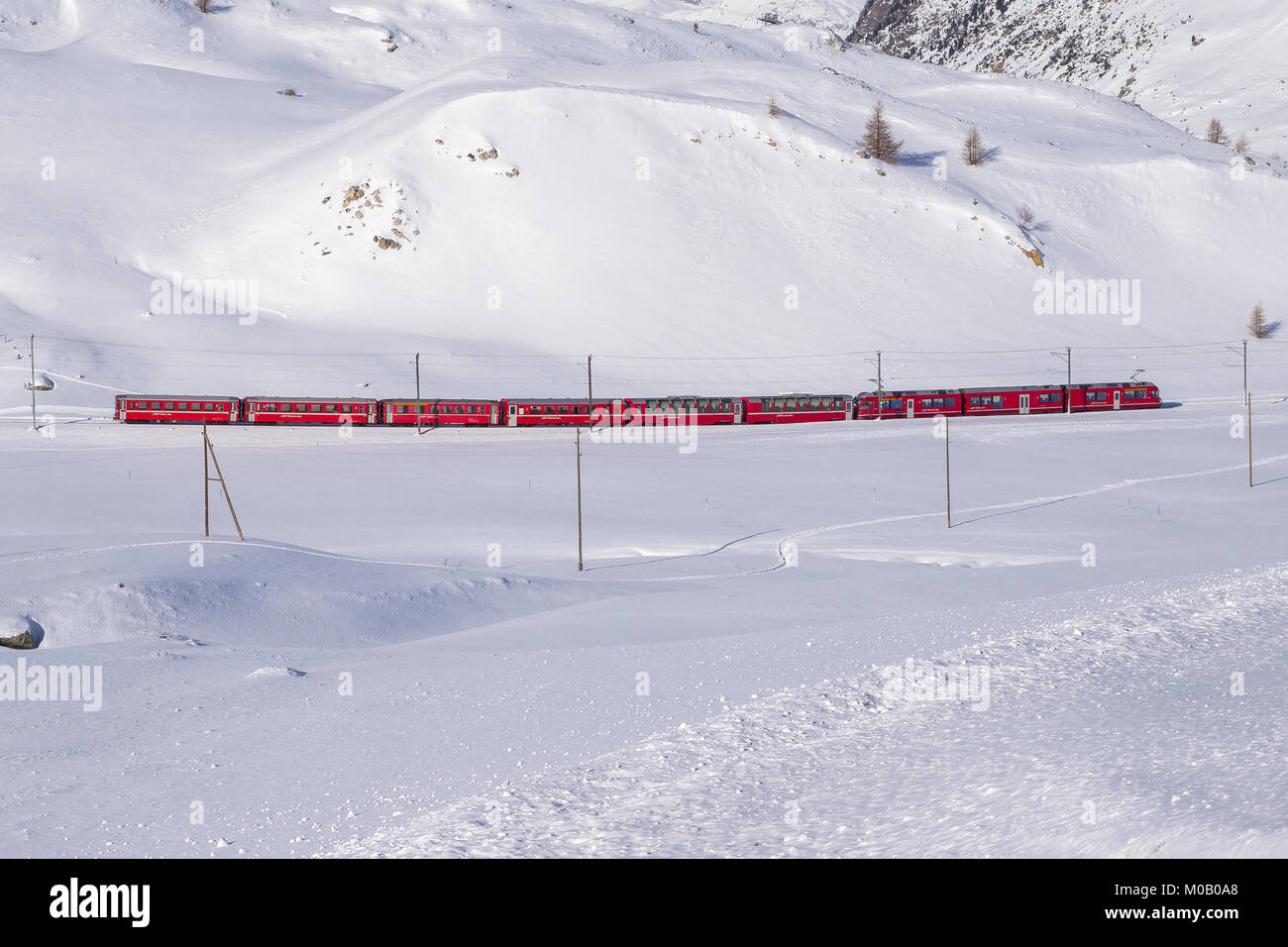Berühmten Bernina Roten Zug zu Fuß durch Schnee Landschaft zwischen Italien und der Schweiz. Stockfoto