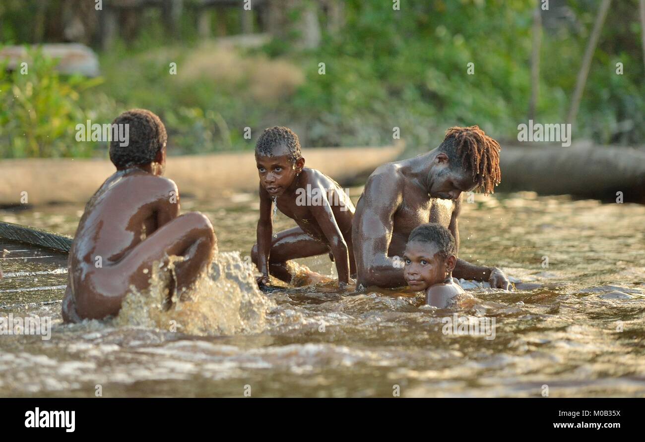 Laut Spaß Kinder. Kinder des Stammes der Asmat Menschen Baden und Schwimmen im Fluss. New Guinea. Stockfoto