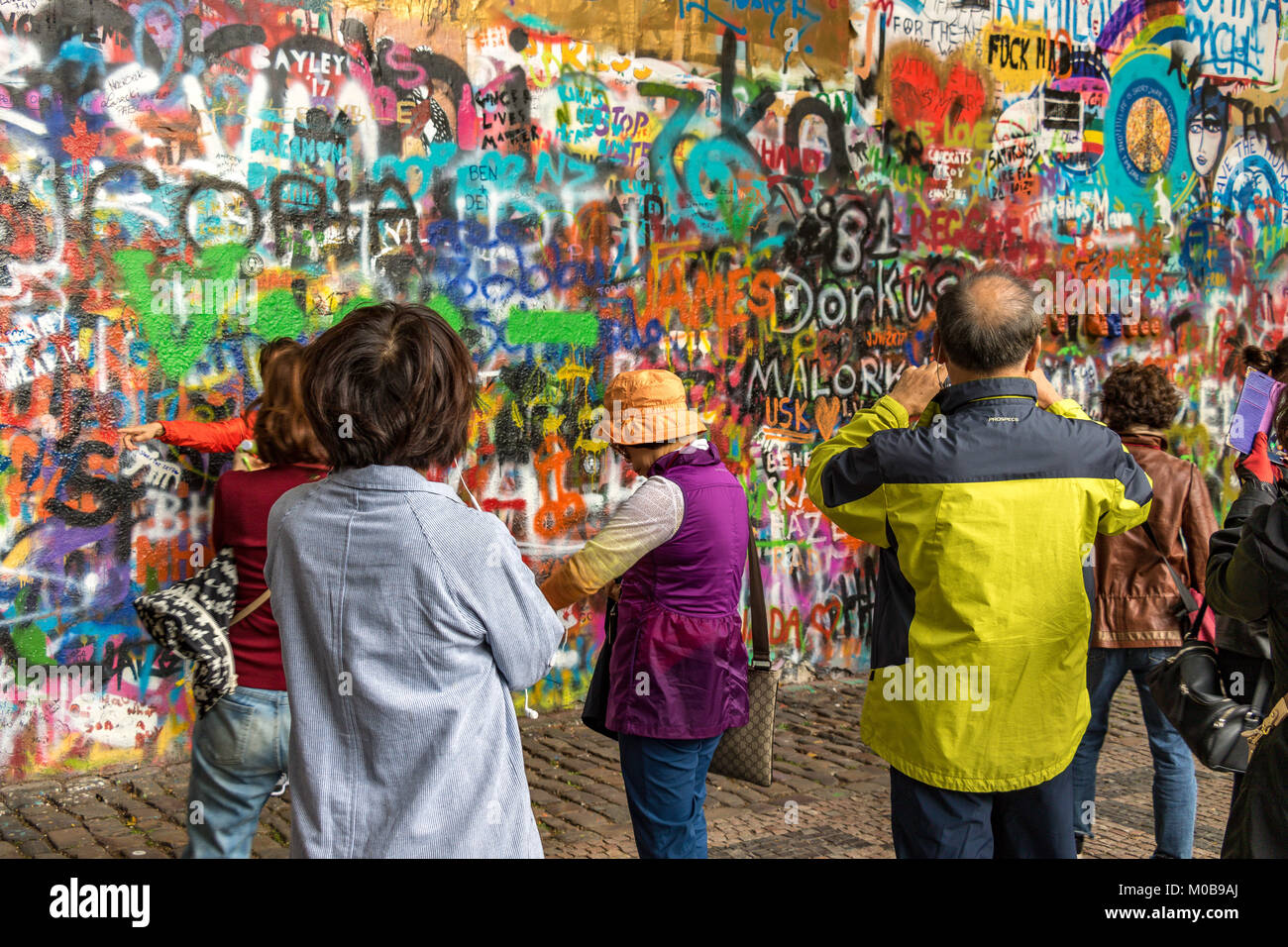 Chinesische Touristen posieren für Fotos vor der mit Graffiti bedeckten John Lennon Wall in Prag, Tschechische Republik Stockfoto