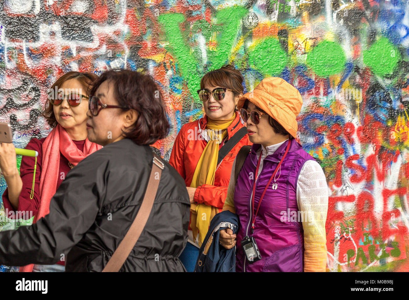 Chinesische Touristen posieren für Fotos vor der mit Graffiti bedeckten John Lennon Wall in Prag, Tschechische Republik Stockfoto