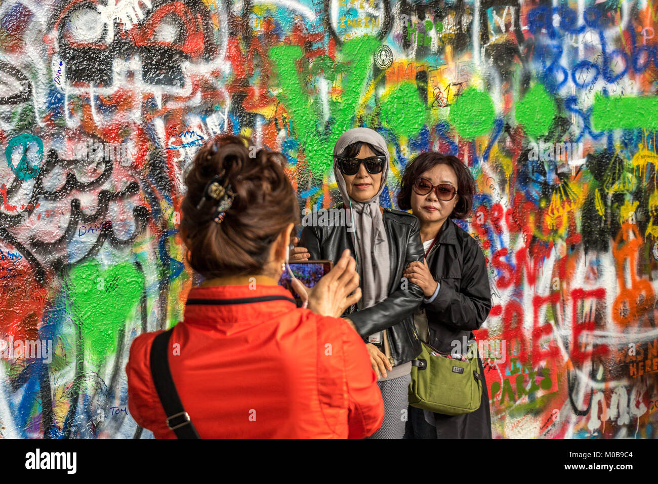 Chinesische Touristen posieren für Fotos vor der mit Graffiti bedeckten John Lennon Wall in Prag, Tschechische Republik Stockfoto