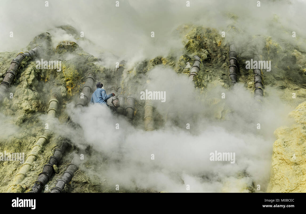 Ranger durch giftige Gase, die versuchen, das überschüssige Rauch aus dem Rohr zu Schwefel erhöht Produktion in Kawah Ijen Berg, Indonesien umgeben Stockfoto