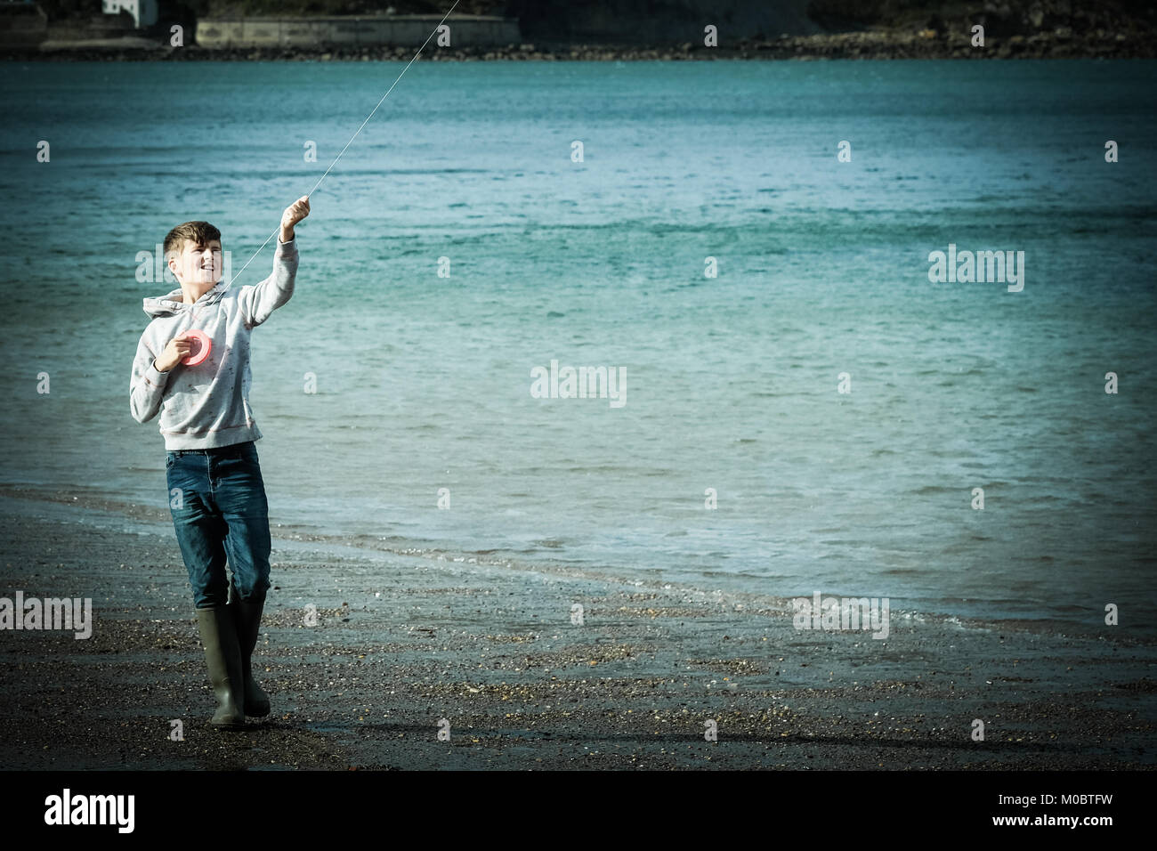 10 Jahre alter Junge flying a Kite durch das Meer bei [Songbook] Bay, Yorkshire, Großbritannien Stockfoto