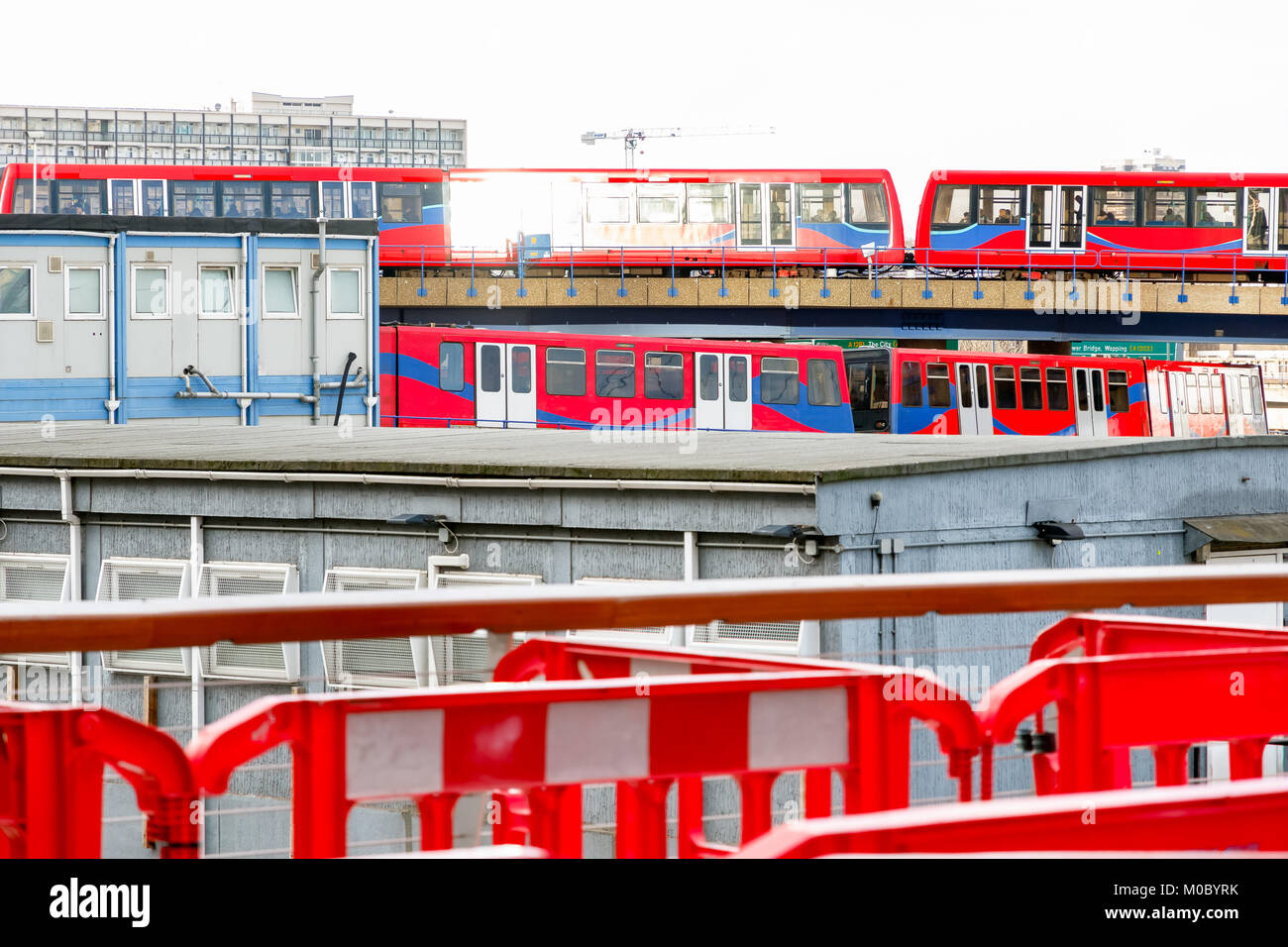 Zwei leichte Züge, die sich kreuzen, durch eine Baustelle in Canary Wharf, London gesehen Stockfoto