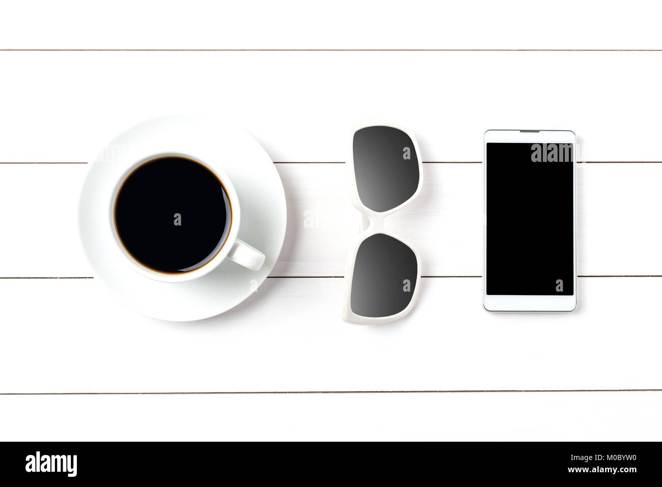 Kaffeetasse, Sonnenbrille und Smart Phone auf weißem Holz- Hintergrund Stockfoto