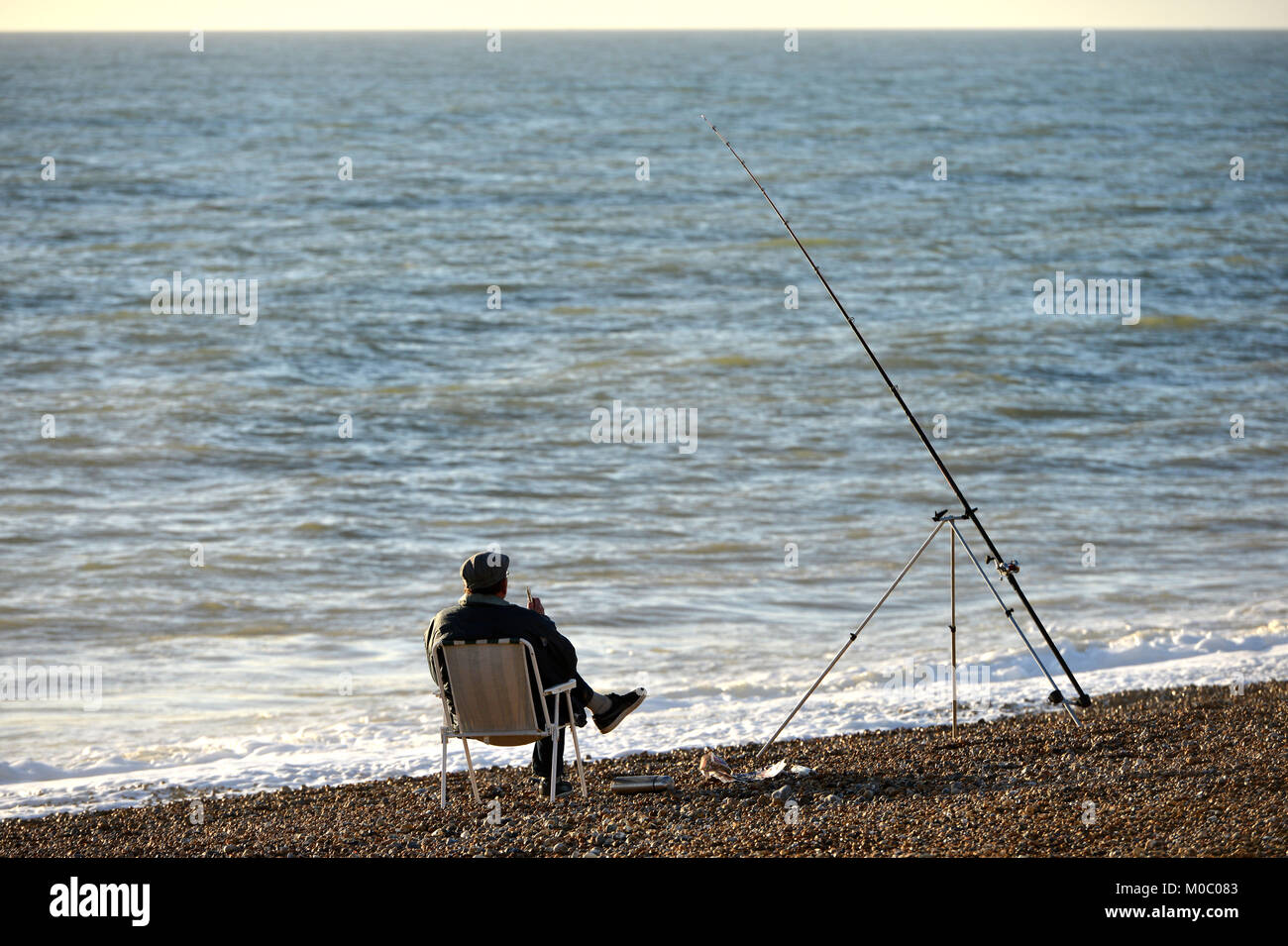 Alter Mann entspannt auf einen Stuhl, während Seefischerei in Seaford, East Sussex. Stockfoto