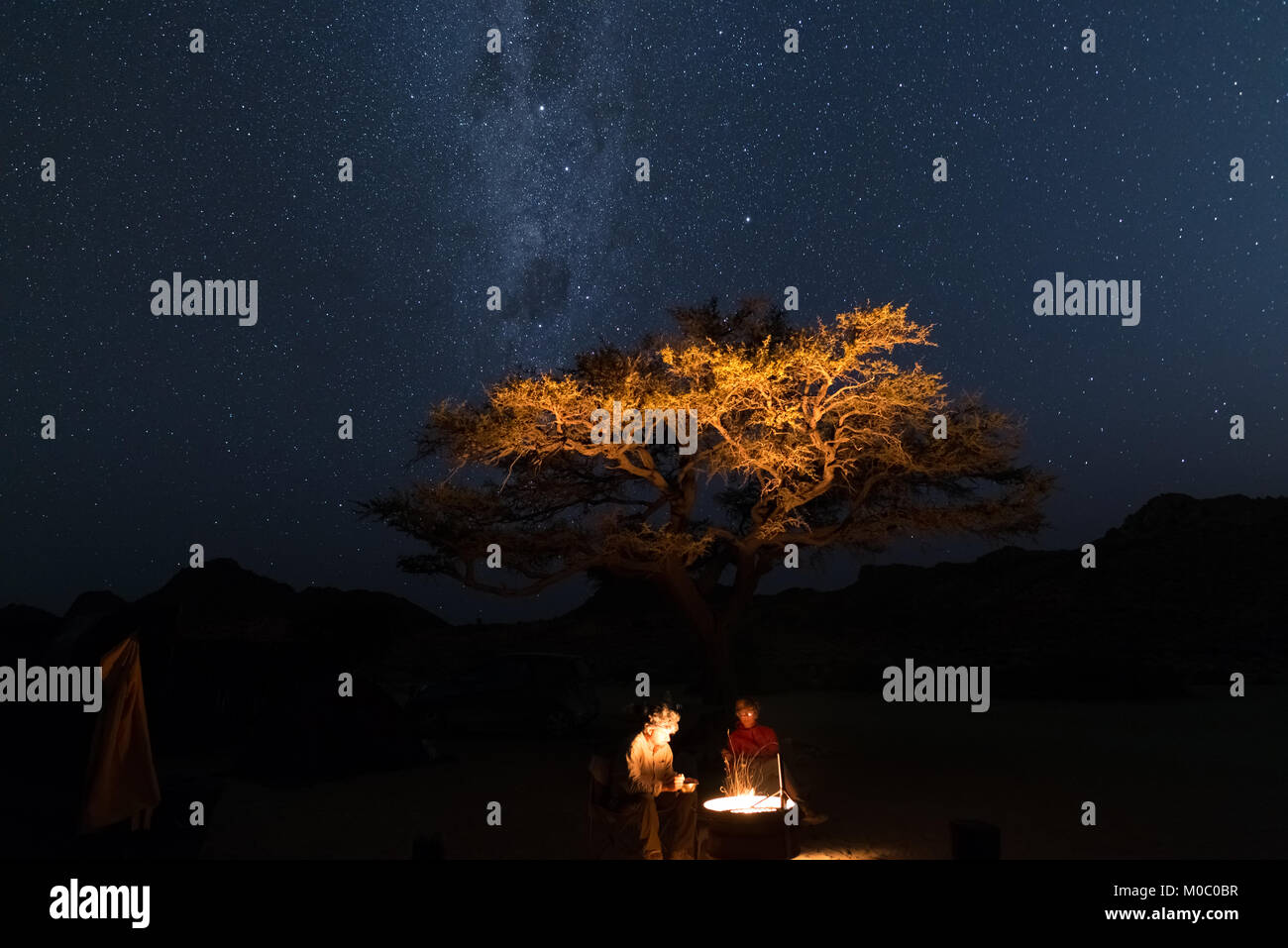 Ehepaar am Lagerfeuer, Camping unter freiem Sternenhimmel und Milky Way arch. Abenteuer in der Wildnis, Namibia Reise, Urlaub in Afrika. Stockfoto