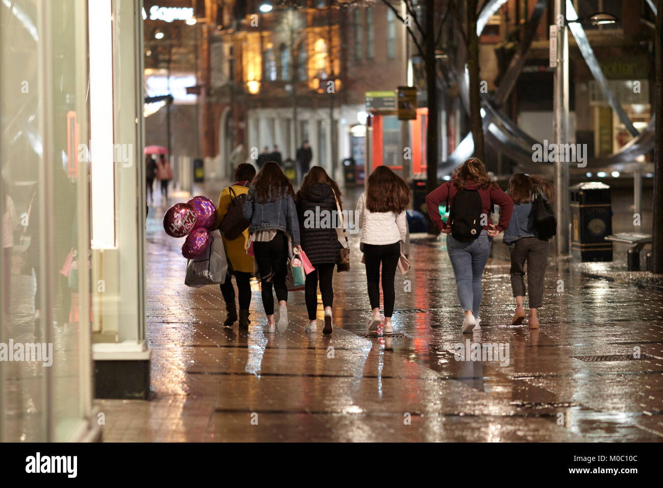 Gruppe von jugendlichen Mädchen, junge Frauen für eine Geburtstagsfeier auf einem nassen Winter Nacht in Belfast Nordirland UK Stockfoto