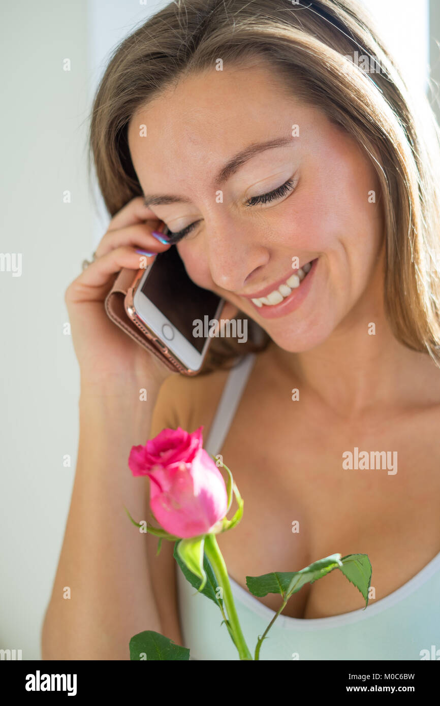 Junge Frau am Telefon mit Blume Stockfoto