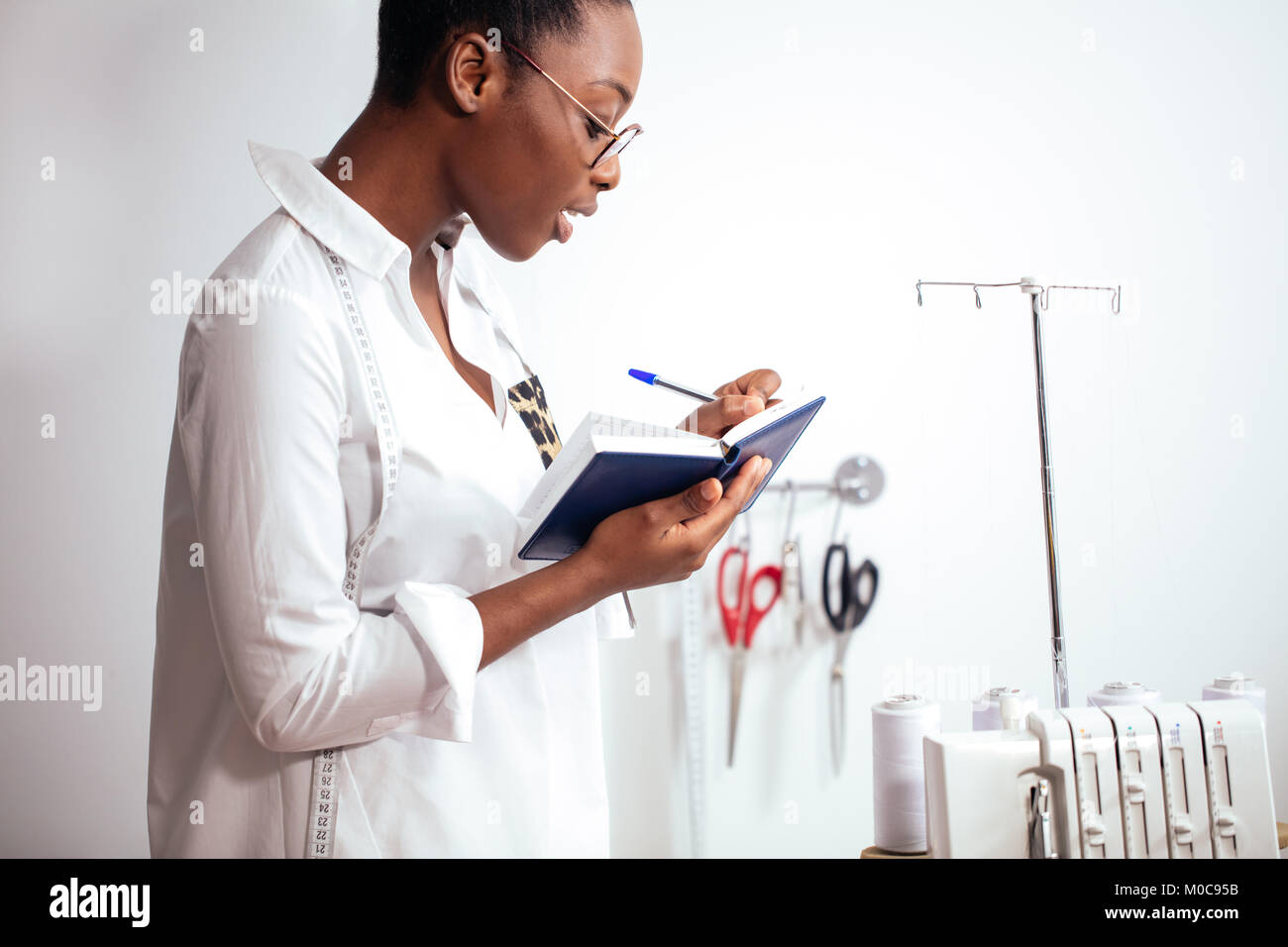 Afrikanisches Mädchen Schneiderin Notizen am Notebook. designer Skizzen Stockfoto
