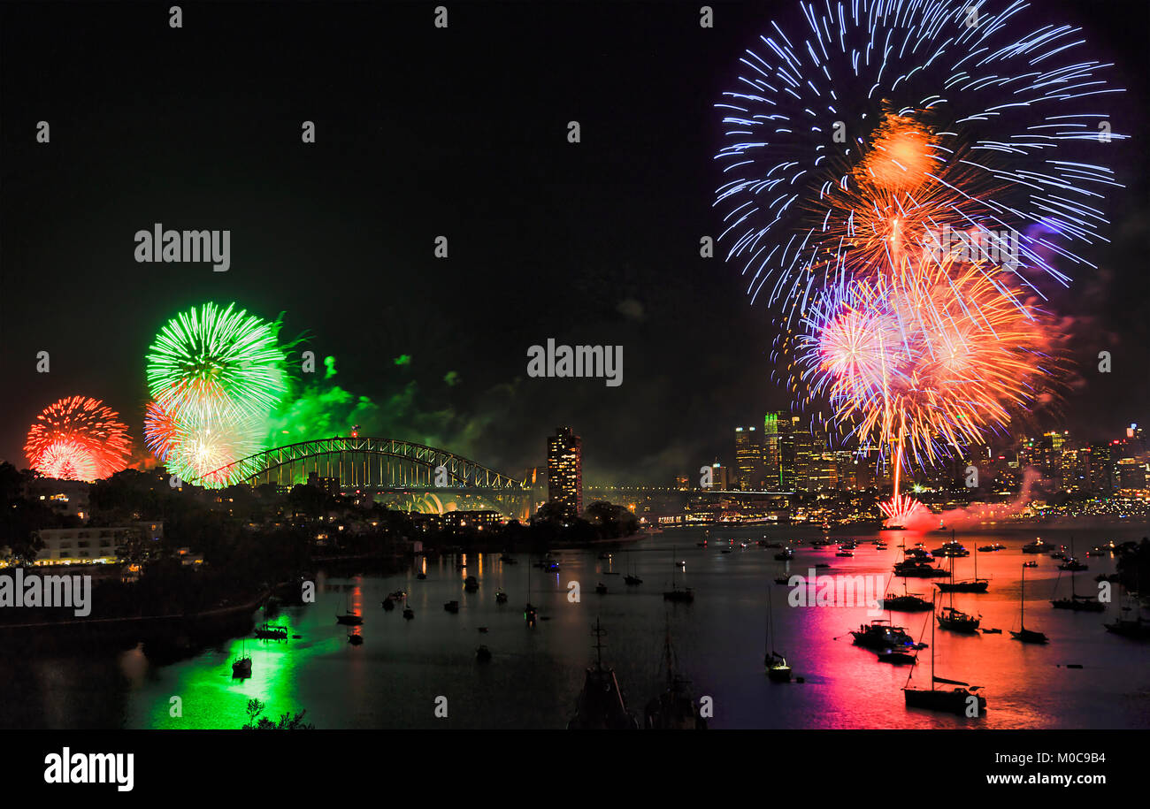Dunkle Silvester Nacht in Sydney CBD mit hellen bunten Feier Feuerwerk blinkenden Himmel und im stillen Wasser des Hafens über Uhr widerspiegelt Stockfoto