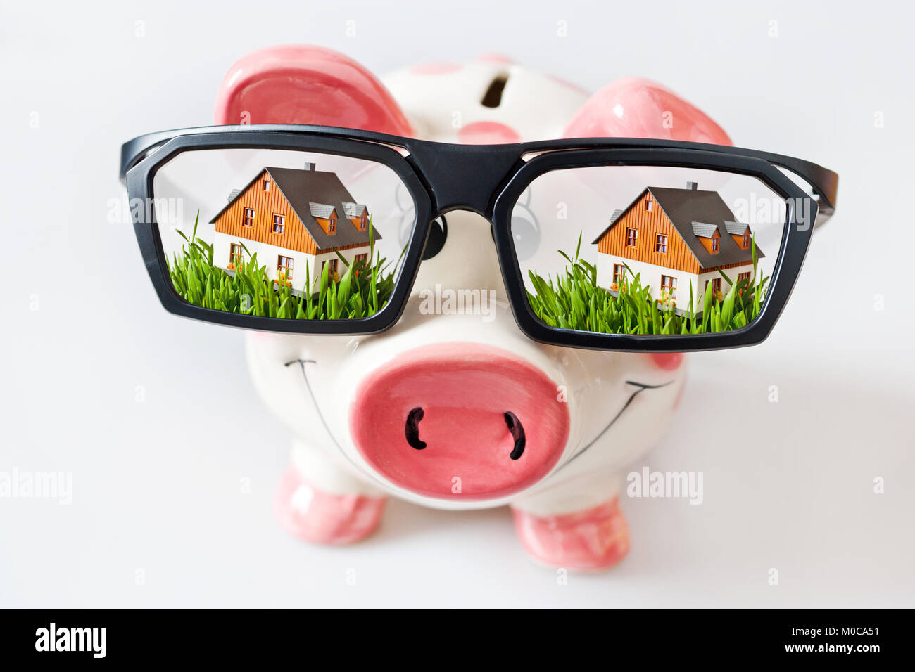 Wirtschaft und Finanzen - Sparschwein mit Brille und geträumt - Einsparungen für ein neues Haus Stockfoto