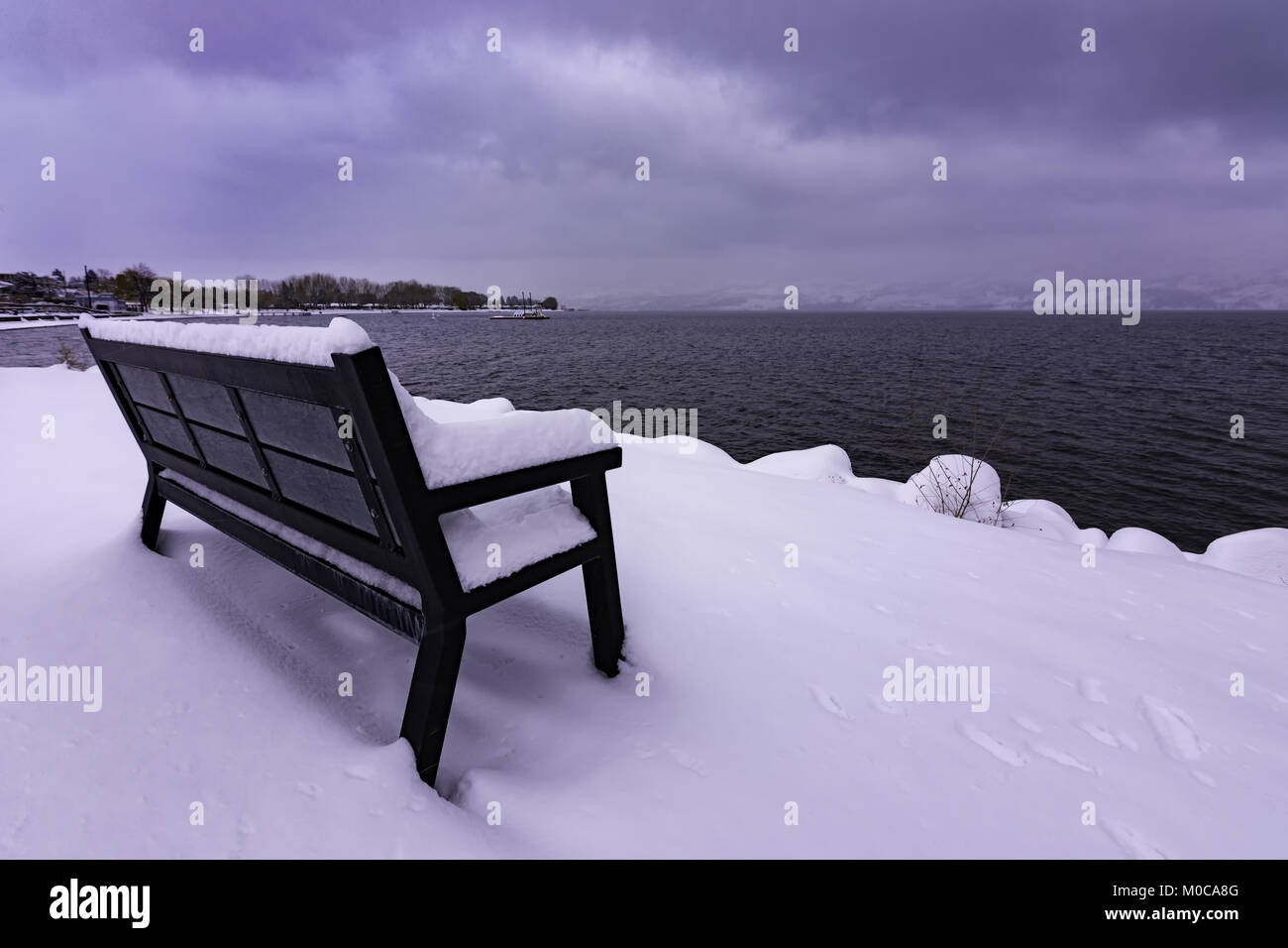 Schneebedeckte Parkbank am Okanagan Lake West Kelowna British Columbia Kanada an einem stürmischen Tag Stockfoto