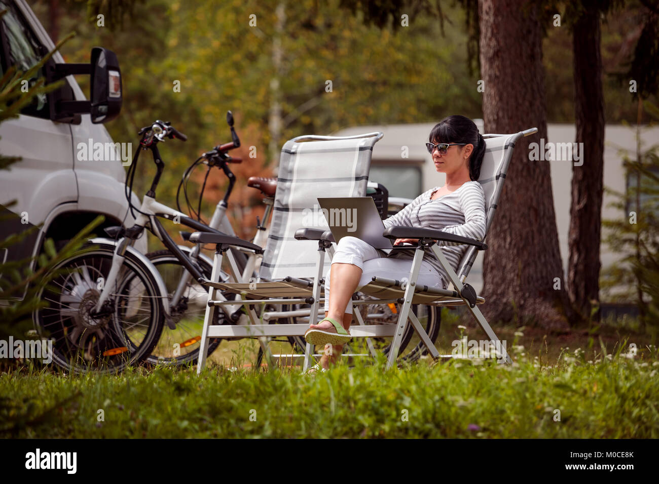 Frau auf dem Laptop in der Nähe des Camping. Caravan Auto Urlaub. Familie Urlaub Reisen, Urlaub im Reisemobil RV. Wi-fi Verbindung Informatio Stockfoto Frau auf dem Laptop in der Nähe des Camping. Caravan Auto Urlaub. Familie Urlaub Reisen, Urlaub im Reisemobil RV. Wi-fi Verbindung Informatio Stockfoto