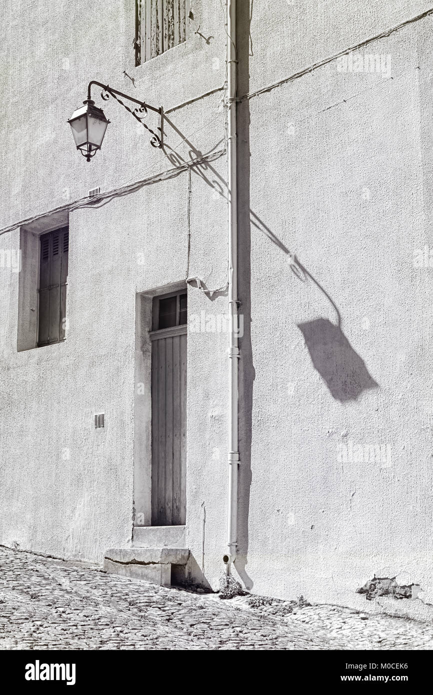 Schwarz-weiß Foto von einer Laterne in voller Sonne auf der Mauer in der Stadt Viviers in der Ardeche Region in Frankreich Stockfoto