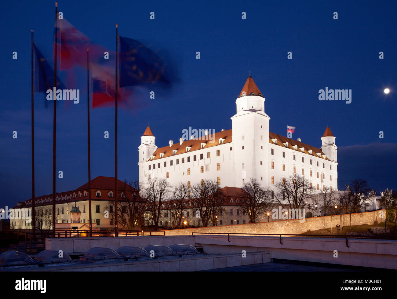 Bratislava - Das Schloss aus dem Parlament in der Nacht und Fahnen. Stockfoto