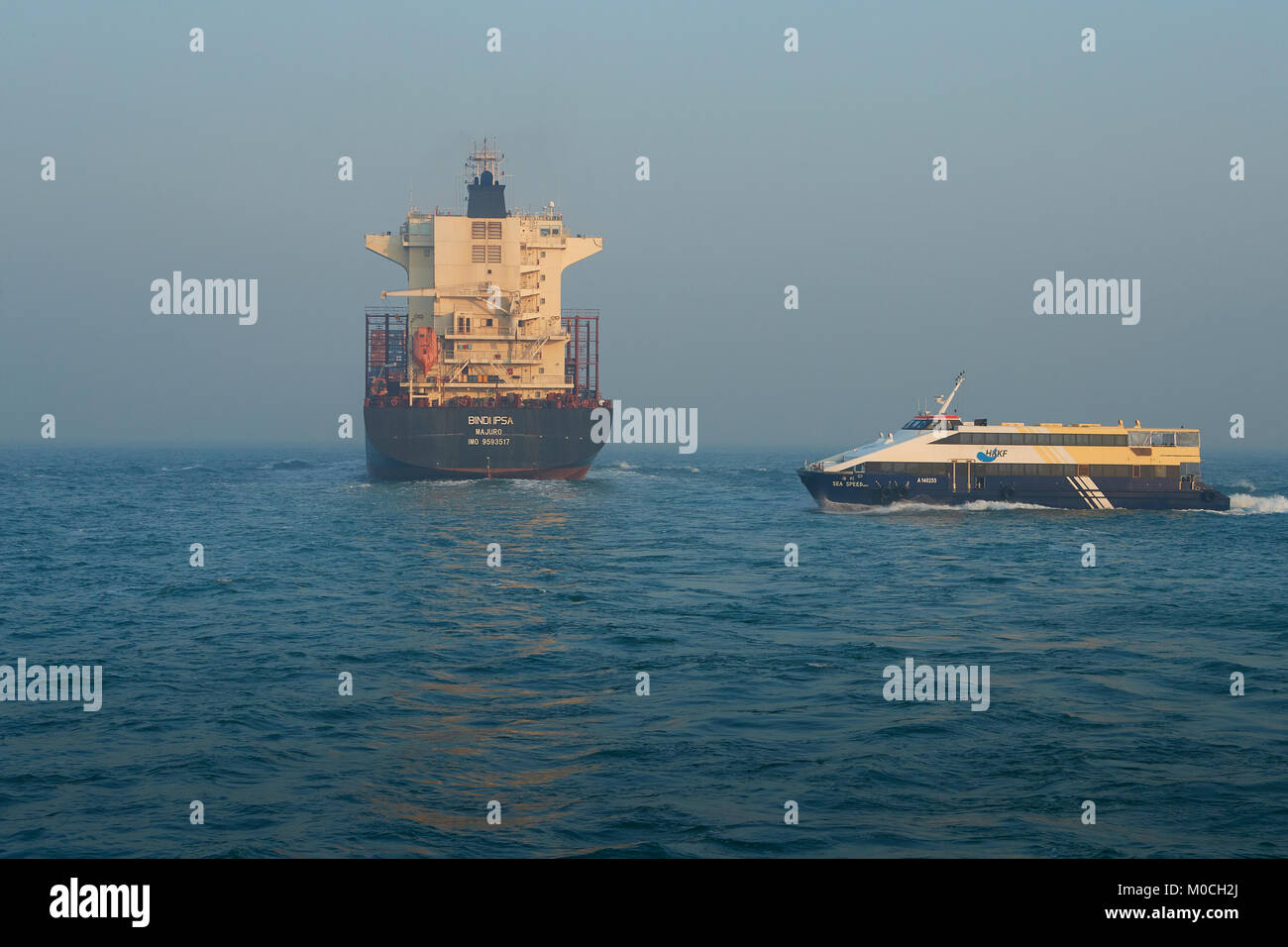 Containerschiff, BINDIIPSA, verlassen den Osten Lamma Kanal, Hongkong, eine lokale SeaCat Fähre vorbei Achteraus. Stockfoto