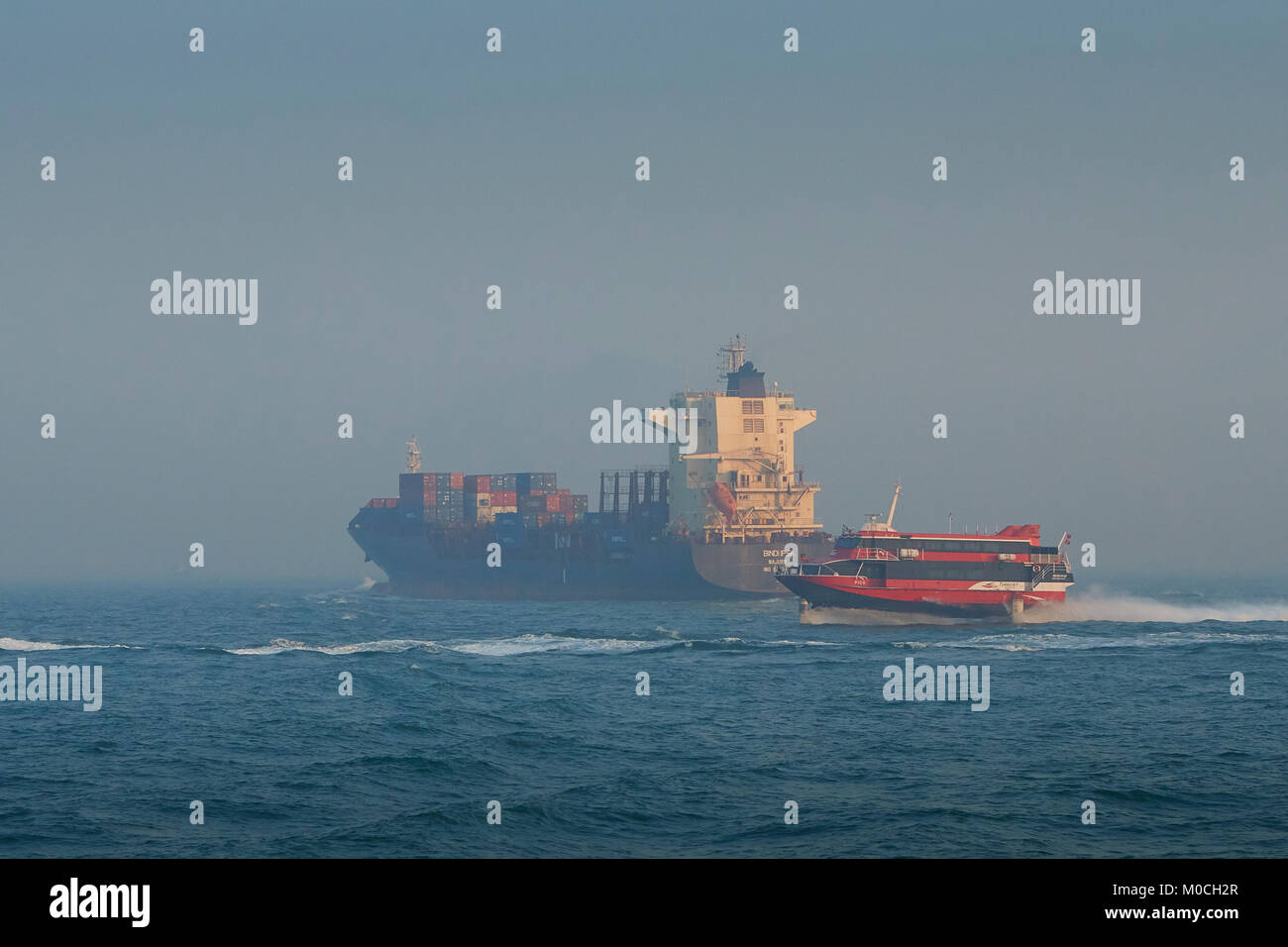 Containerschiff, BINDIIPSA, verlässt East Lamma Channel, Hong Kong. Eine Boeing Jetfoli-Passagierfähre mit Turbojet fährt nach Macau, hinter China vorbei Stockfoto