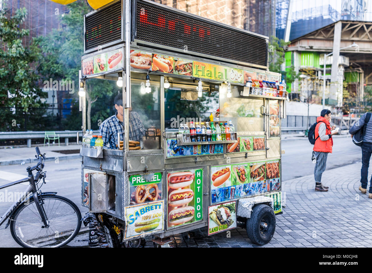 New York City, USA - 27. Oktober 2017: Mann Anbieter hinter Halal fast food Truck in NYC im Chelsea West Side von Hudson Yards, mit Menschen zu Fuß in Eve Stockfoto