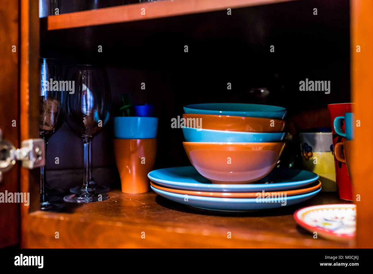 Offene Küche aus Holz Schranktür Schrank mit vielen bunten Teller, Schüsseln, Teller, Tassen, Gläser, die auf Regalen closeup Stockfoto