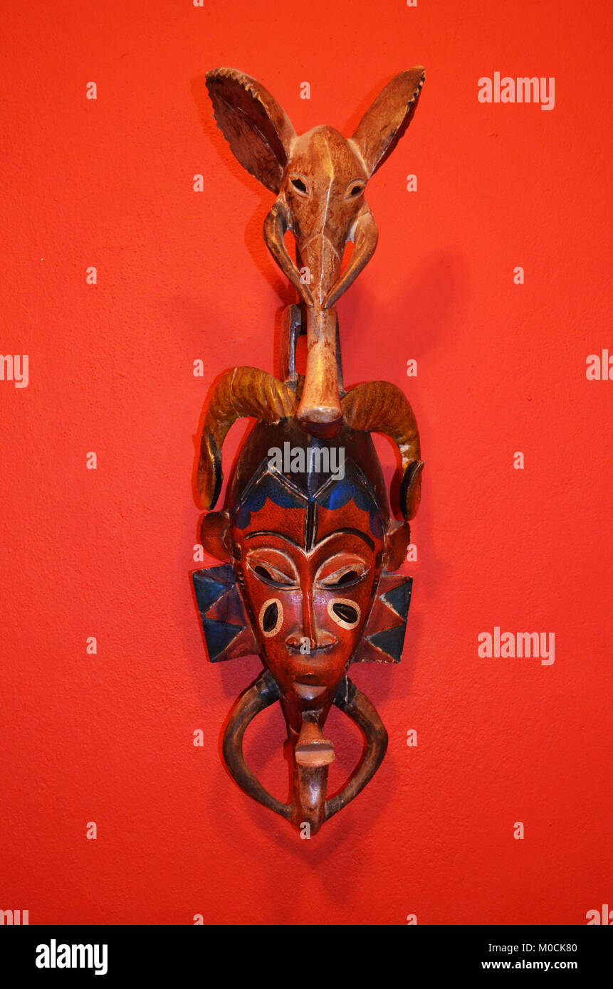 Afrikanische Maske auf einem roten Hintergrund isoliert. Stockfoto