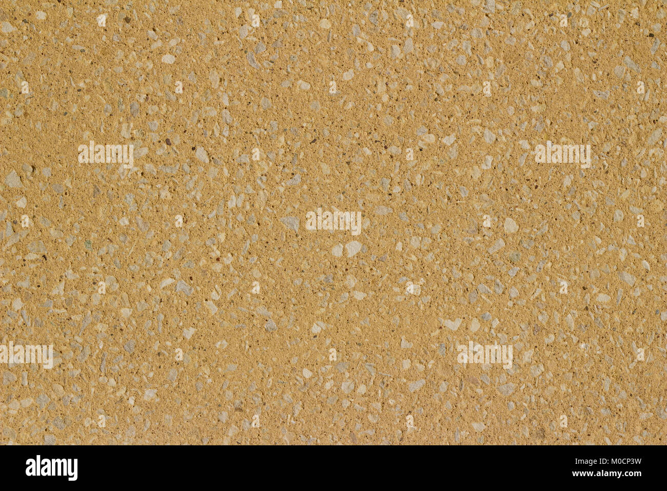 Sandfarbene tan Stuck Wand Hintergrund mit freiliegenden Steinen auf seiner Oberfläche Stockfoto