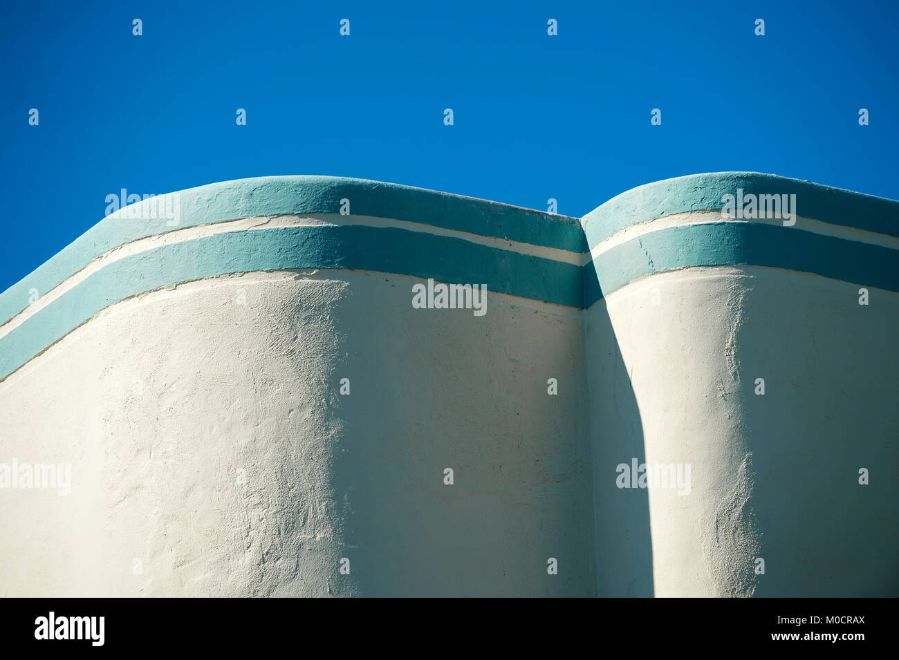 Abstrakte Architektur Nahaufnahme einer geschwungenen Art déco-Wand mit Mediterranean Blue Stripe detail gekrönt unter hellen Himmel Stockfoto