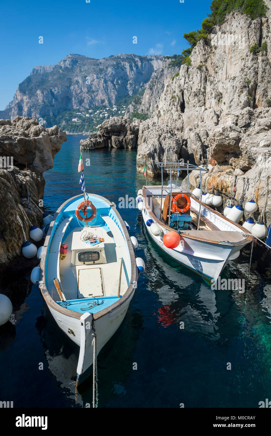 Hell gestrichenen Wassertaxis mit bunten Zubehör angedockt in einer felsigen Bucht im Mittelmeer auf der Insel Capri, Italien Stockfoto