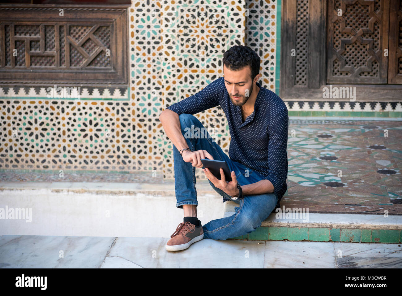 Casual arabischen Mann bei der Arbeit auf Tablet sitzen auf dem Boden Stockfoto