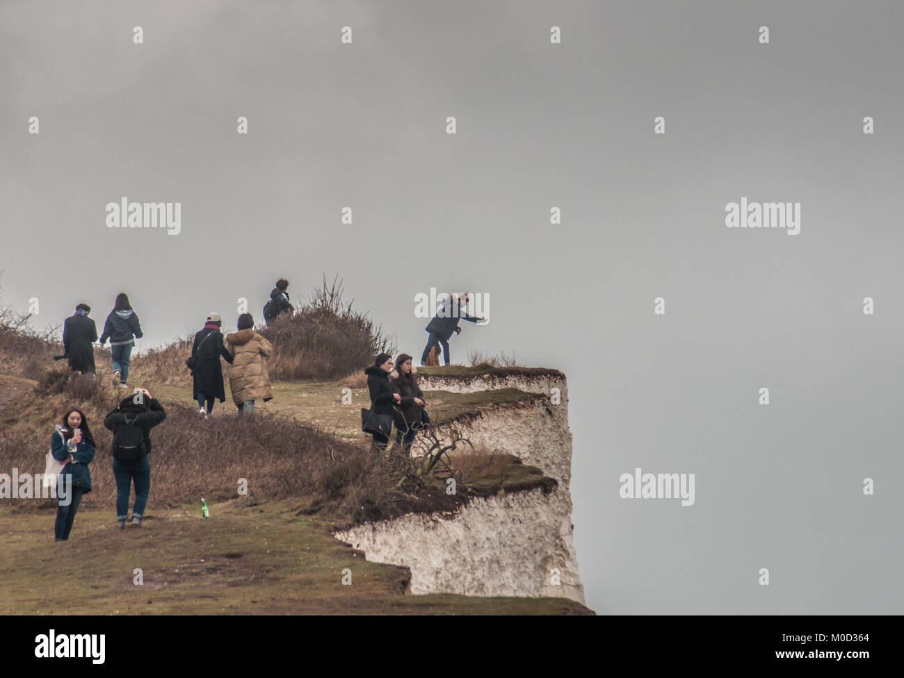 Birling Gap, East Sussex, Großbritannien 20. Januar 2018. Die Erosion der Kreidefelsen setzt sich mit häufigen Felsstürmen fort, Unterschneidung und Fissuren. Viele Besucher des South Coast Beauty Spot kommen gefährlich nahe an die fragile Klippe. Neue zusätzliche temporäre Warnschilder sind verschwunden und wurden nicht ersetzt. Es scheint, dass die alte Beschilderung unzureichend ist und nicht für Hunderte von ausländischen Besuchern geeignet ist. Der Fotograf wurde darauf hingewiesen, dass zwischen National Trust und Local Council Gespräche über Beschilderung laufen. Stockfoto