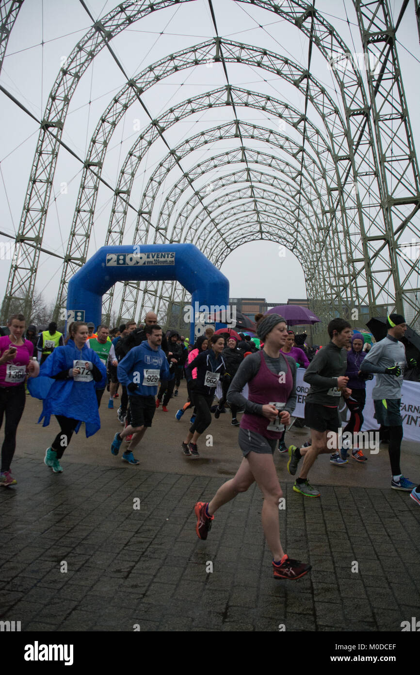 Farnborough, Hampshire, Großbritannien. 21. Januar 2018. Schnee und Schnee für den 2. Farnborough Winter Halbmarathon. Viele Läufer und Zuschauer kamen trotz des winterlichen Wetters. Das Rennen begann und endete unter dem berühmten Luftschiff Hangar im Farnborough Business Park. Stockfoto