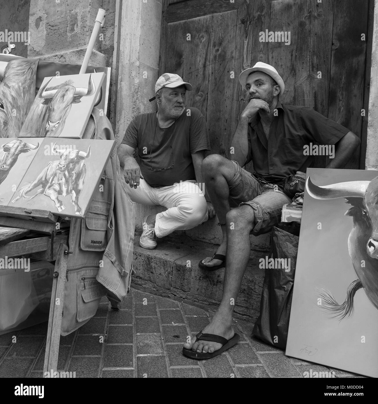 Zwei Künstler sitzen plaudernd in Spanisch Straße im touristischen Bereich angezeigte Gemälde zum Verkauf - monochrom Street Fotografie Stockfoto