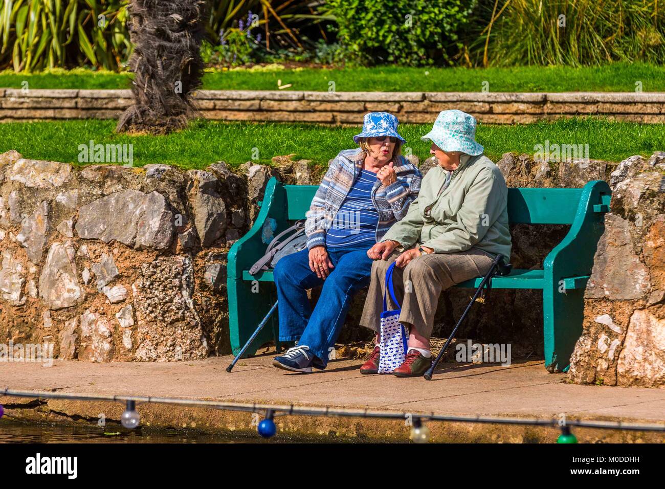 Zwei Frauen Freunde Chat auf einen Garten oder Park Bench. Stockfoto