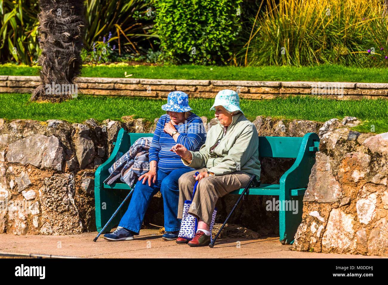 Zwei Frauen Freunde Chat auf einen Garten oder Park Bench. Stockfoto