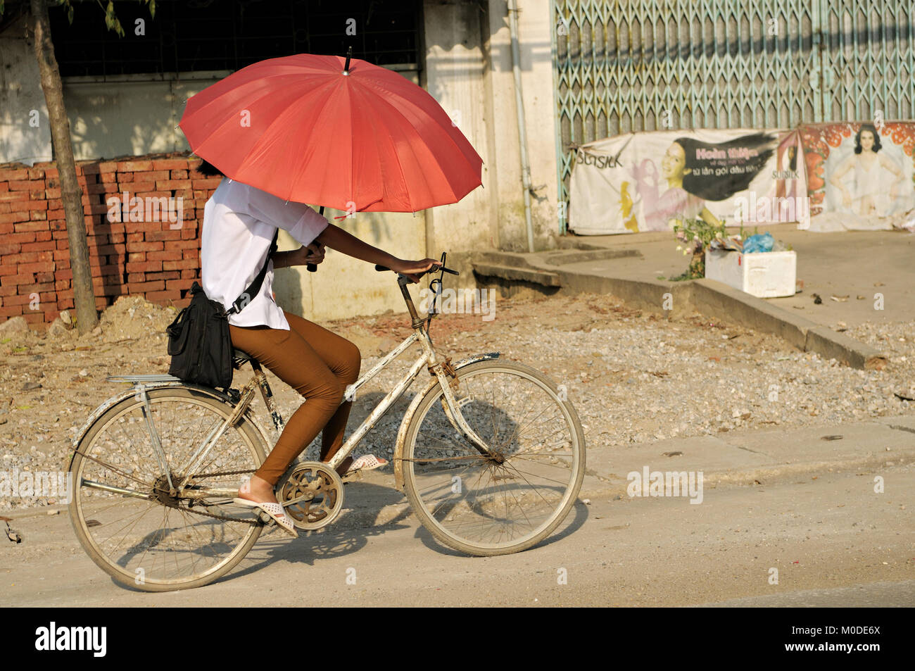 Junge Frau auf einem Fahrrad mit einem roten Regenschirm, North Vietnam Stockfoto