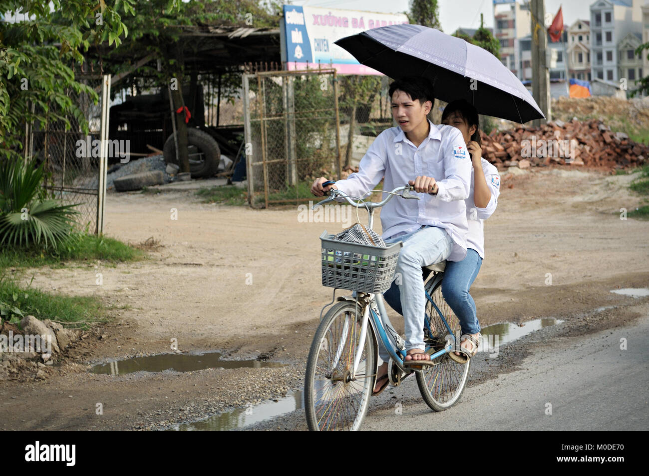 Zwei Studenten auf ein Fahrrad mit einem Regenschirm, North Vietnam Stockfoto