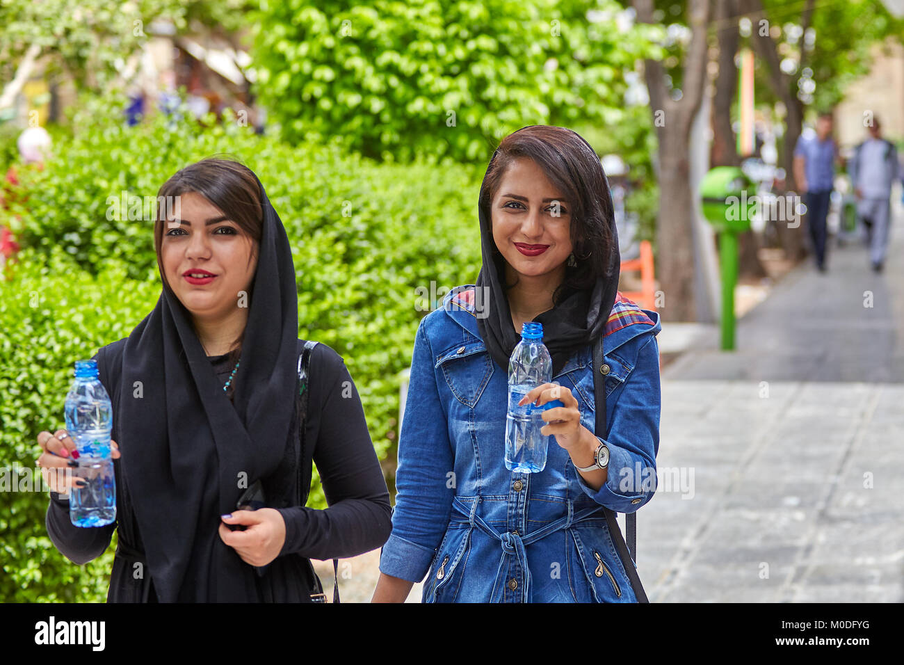 Isfahan, Iran - 24. April 2017: Zwei Iranische muslimische Mädchen, in gezwungen Hijab bekleidet, Verwenden Sie abgefülltes Wasser, Wandern im Park. Stockfoto