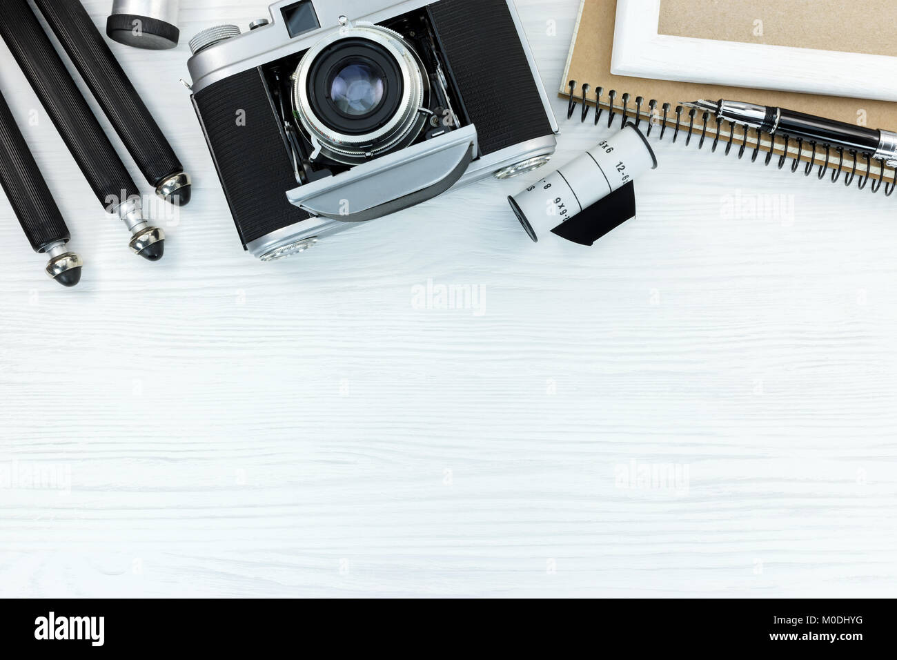 Retro Kamera, Film Roll, Stativ, Notizbuch und Stift auf weißem Hintergrund Holz nach oben verlegen Stockfoto