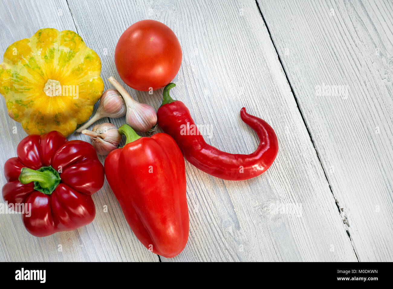 Rote, gelbe und grüne Bush, Kürbisse, Paprika, auf weißem Holz Hintergrund Knoblauch. Garten, Agrar- und Landwirtschaft Konzept. Stockfoto