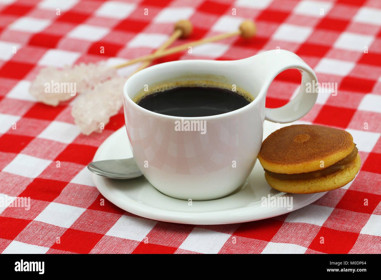 Tasse schwarzen Kaffee in weiße Tasse und schwarze Bohne Cookie auf rot-weiß-karierten Tuch Stockfoto