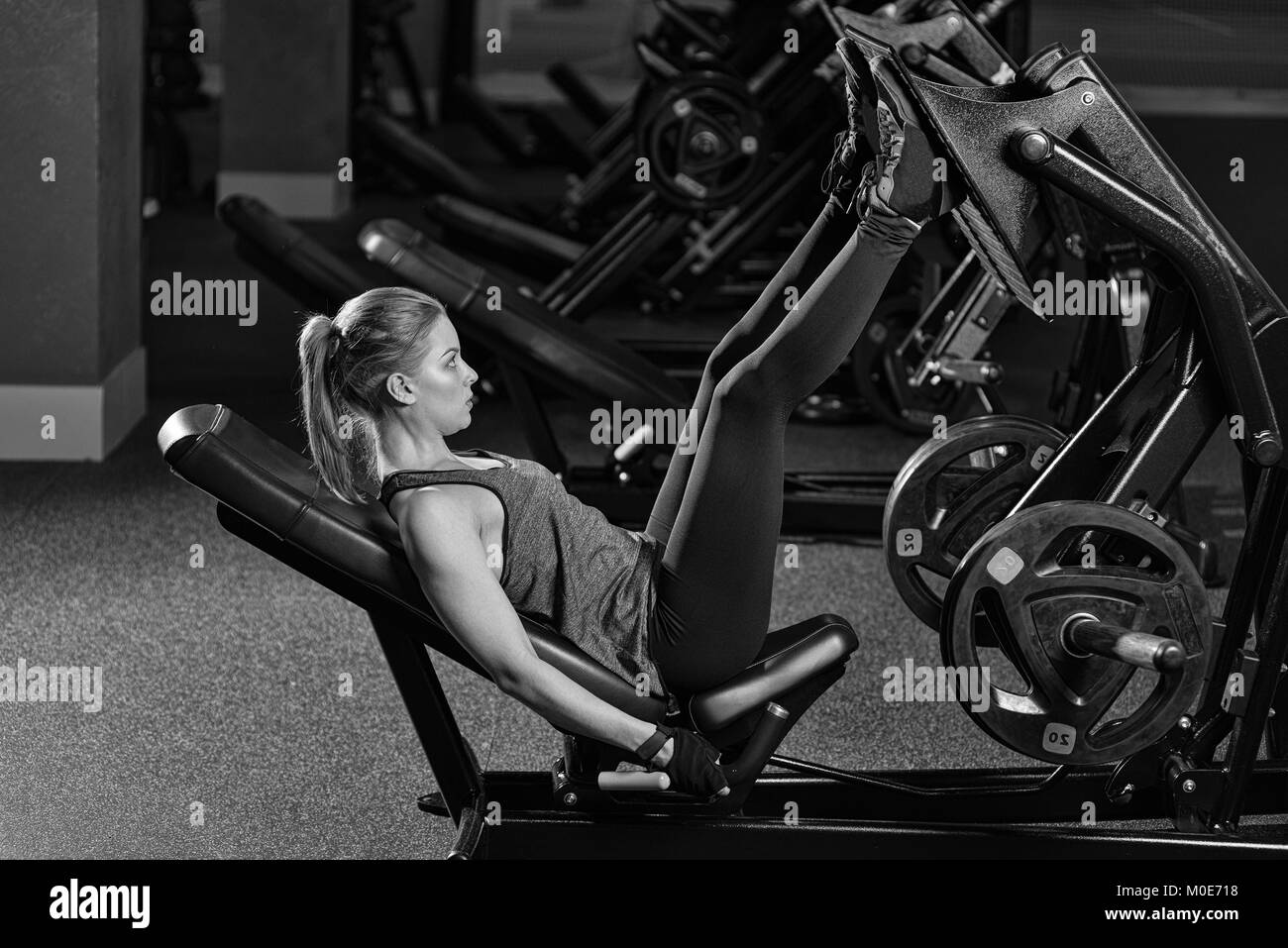 Sportliche Frau mit Gewichten-Presse-Maschine für die Beine. Fitness-Studio. Stockfoto