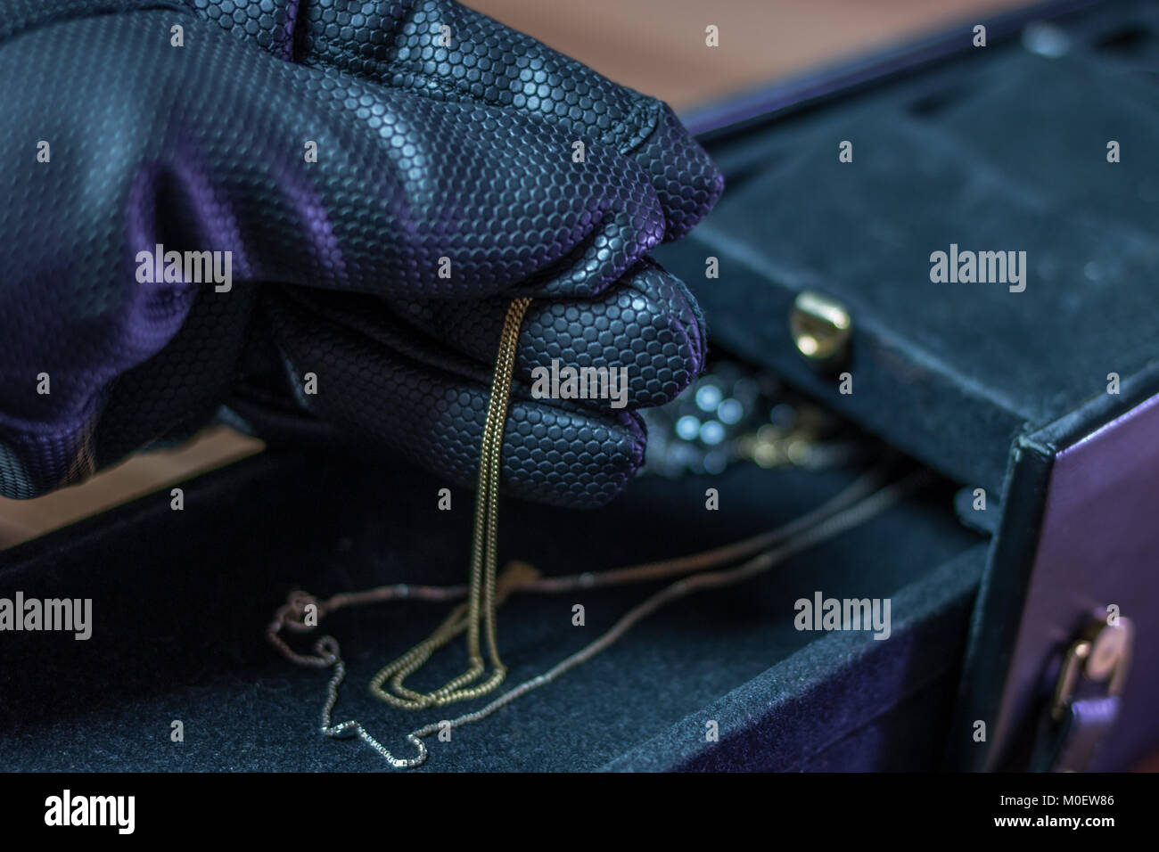 Ein Einbrecher stiehlt Schmuck aus einer Schatulle mit Handschuhen Stockfoto