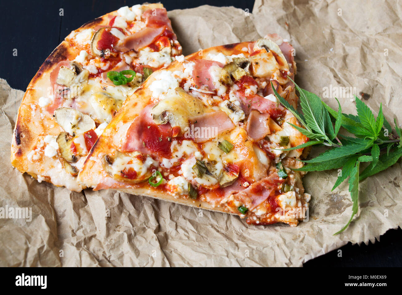 Pizza Scheiben mit Marihuana Blätter auf Papier Stockfoto