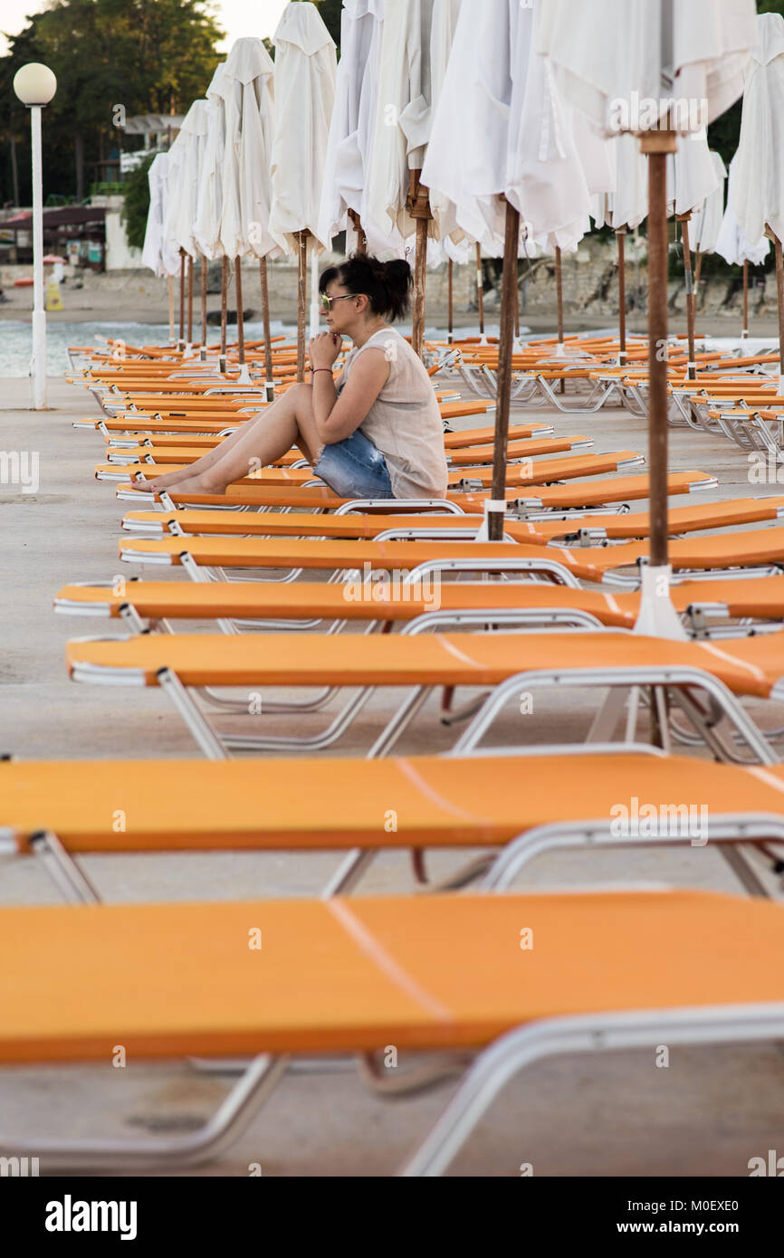 Frau sitzt auf einem Liegestuhl am Strand Stockfoto