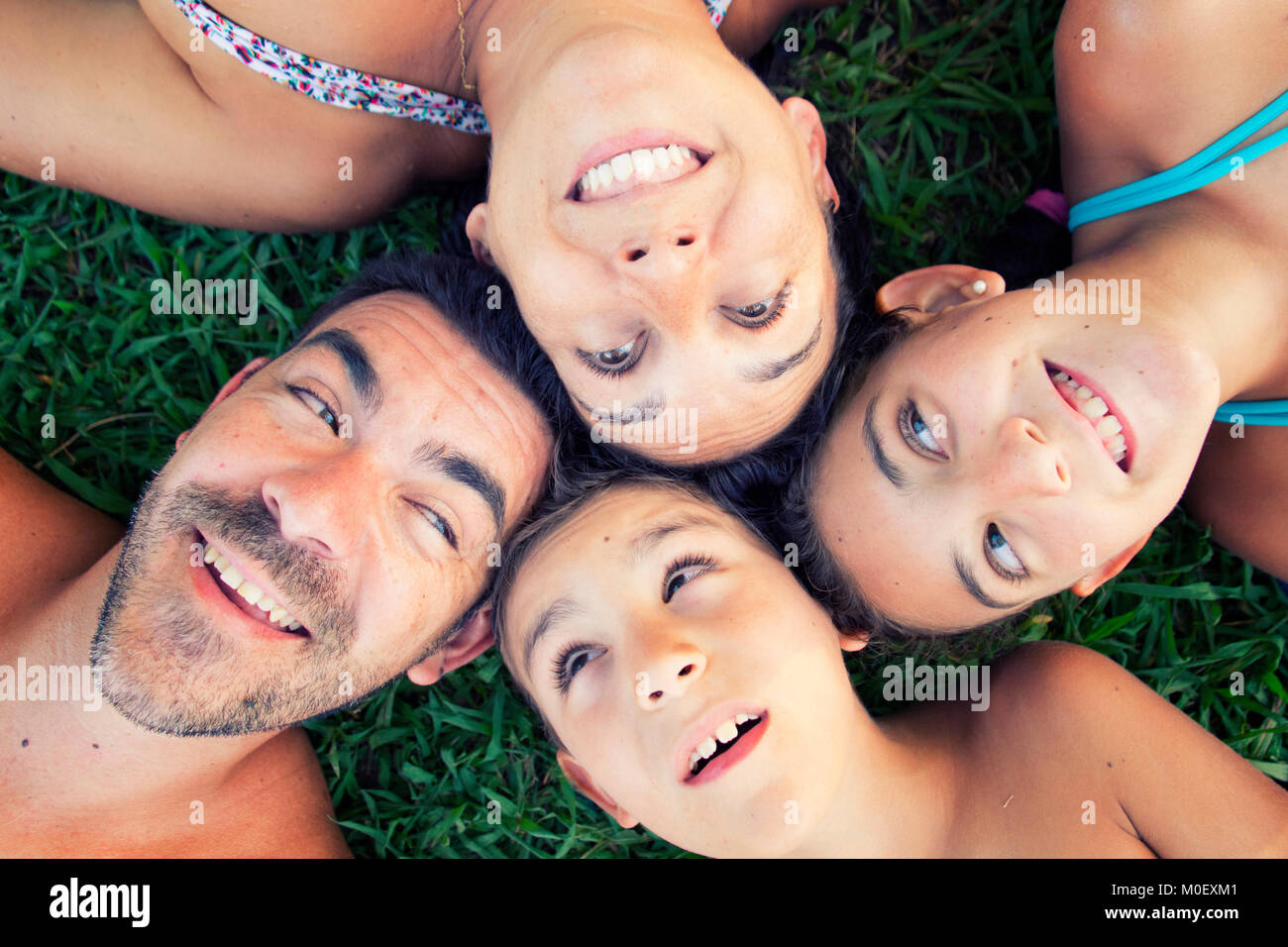 Overhead Porträt einer glücklichen Familie, die auf dem Gras Stockfoto