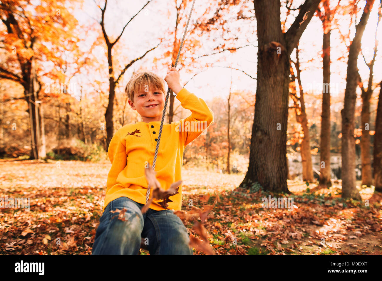Junge sitzt auf einer Schaukel im Garten Stockfoto