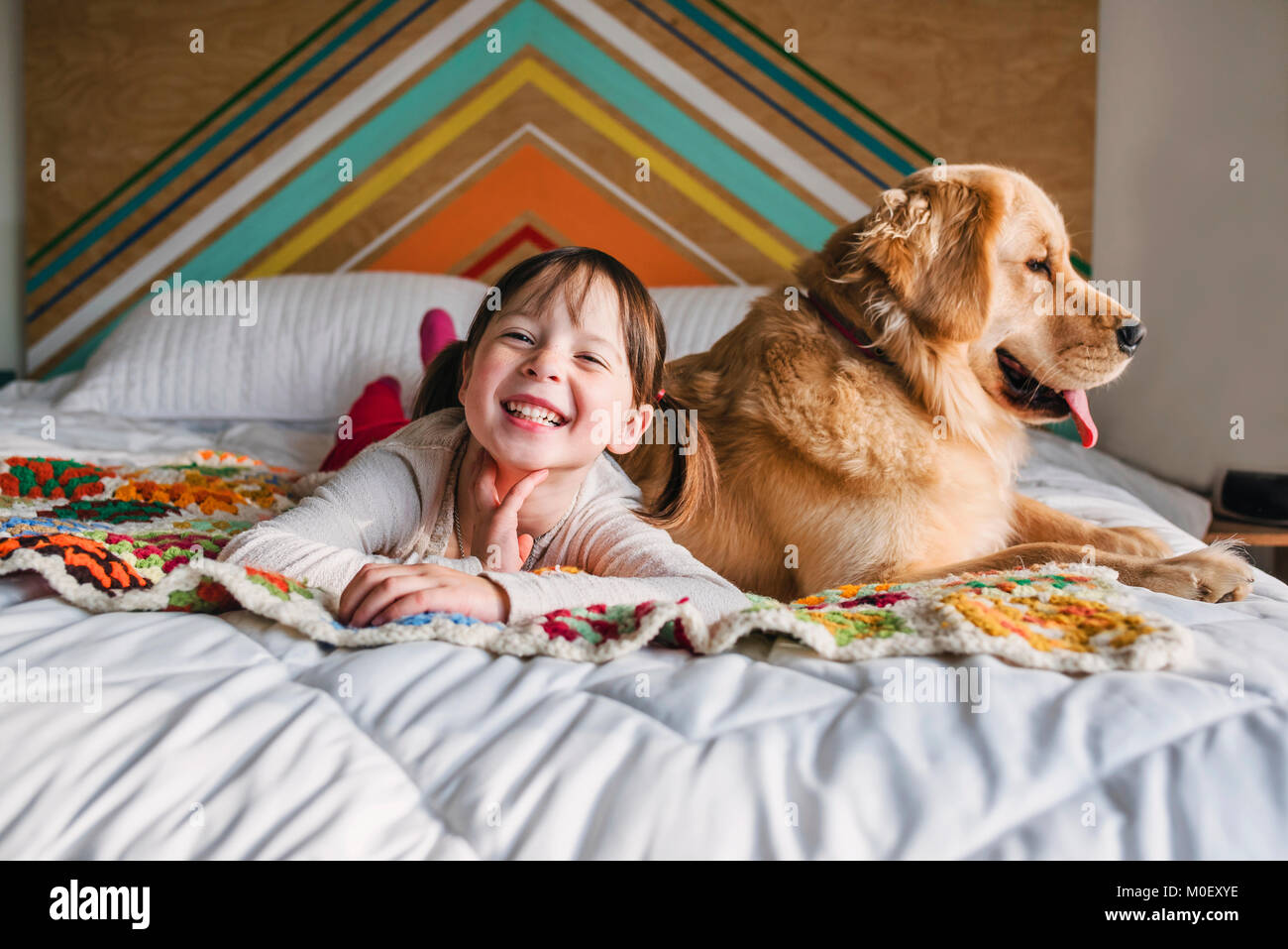 Mädchen liegt auf einem Bett mit ihrem Golden Retriever Hund Stockfoto
